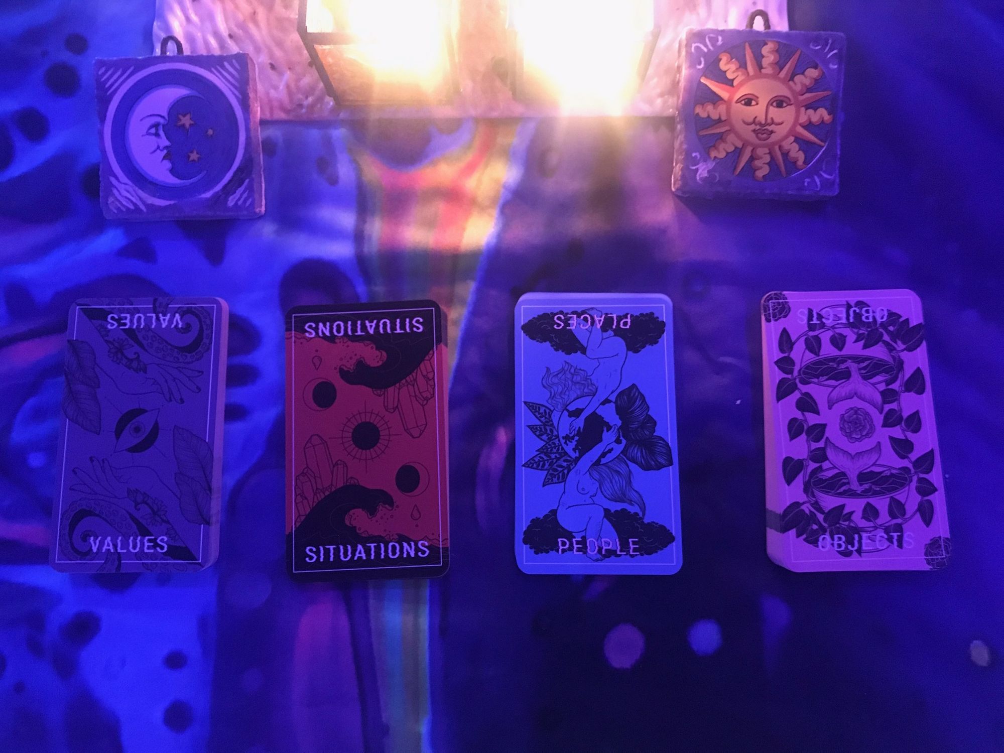 Four cards, with the words Values, Situations, Places, and Objects. Above them, two small ceramic tiles with a moon on the left and a sun on the right, and candlelight between them.
