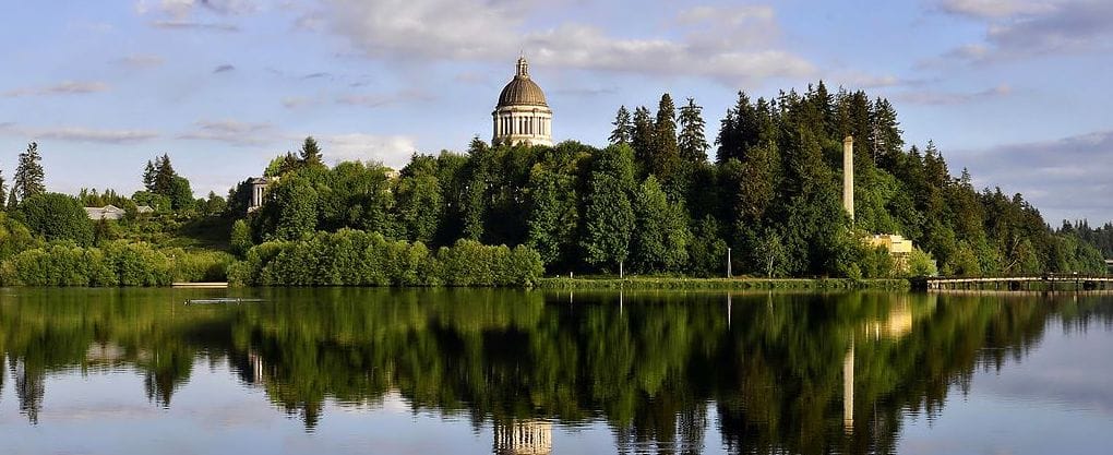 The State Capitol in Olympia: a building with a dome, and lots of trees aroud it, reflected in in a pond