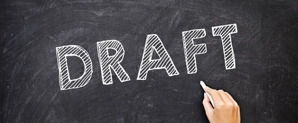A chalkboard with the word Draft on it.  Below, a hand with a piece of chalk.